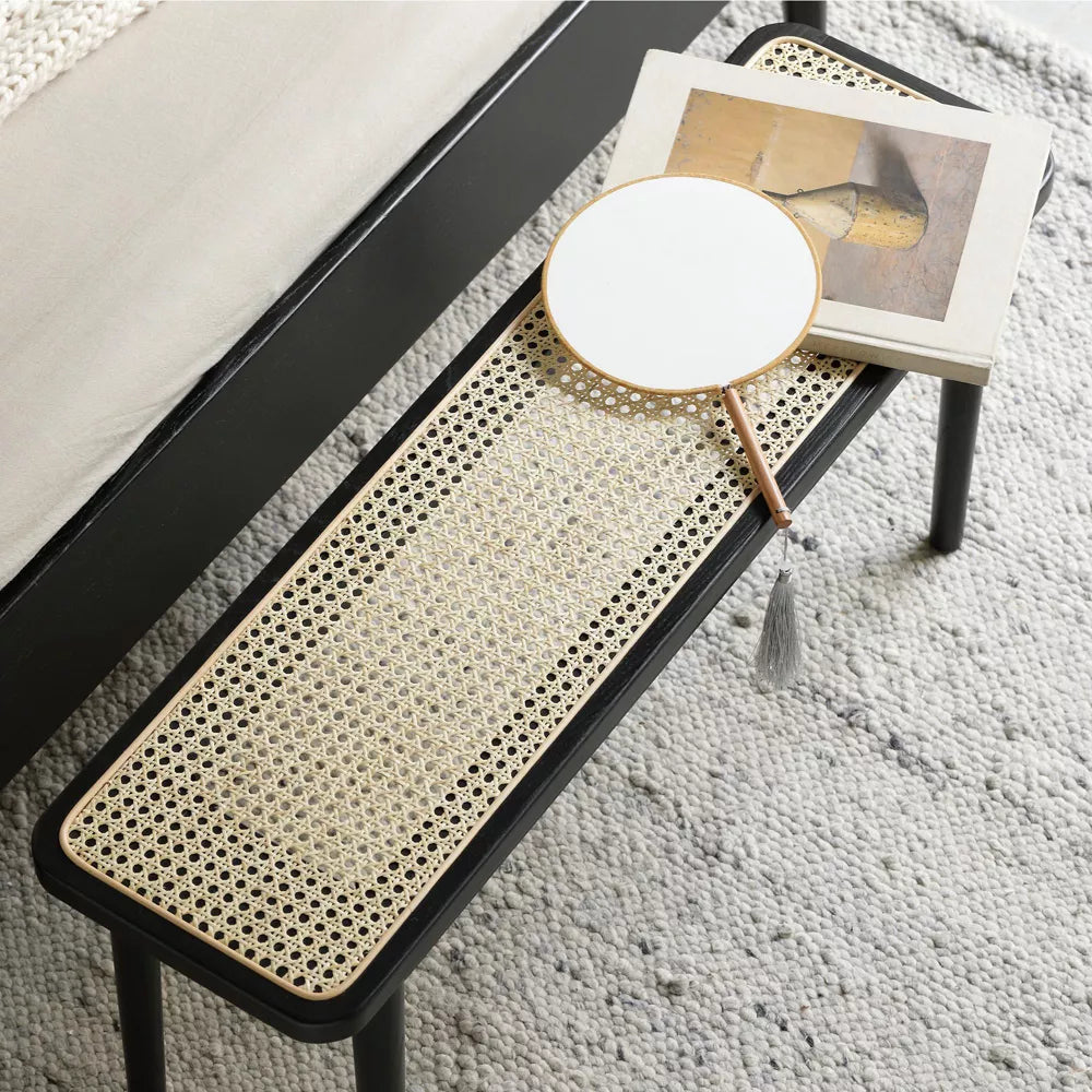 Bench with woven seat and black frame on a carpeted floor